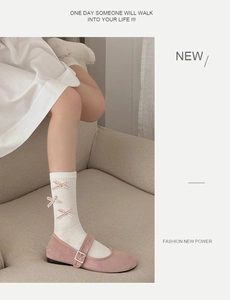 Close-up of white mid-calf socks with pink velvet bows and pink Mary Jane shoes
