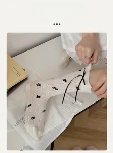 Detail of white Japanese style crew socks with black ribbon bow and bear embroidery