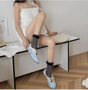 Detail of grey knitted calf socks with black lace trim paired with blue ballet flat shoes