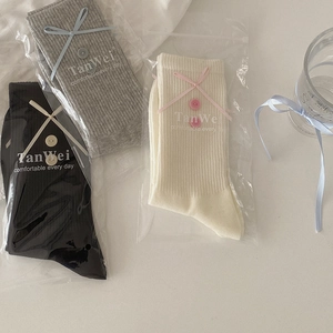 Chic knit mid-calf socks with ribbon bows and buttons in black, grey, and cream white
