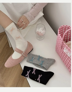 Detail of ribbed knit crew socks with velvet bows paired with pink Mary Jane shoes