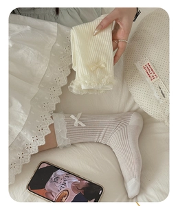 Detailed view of cream rib-knit socks featuring delicate lace edges and a sweet bow