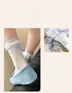 Detail of ballet style lace socks with blue bow ties and cute bear patterns on a soft fabric