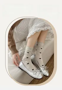 Détail de chaussettes mi-hautes gris clair avec motifs cœurs et bordure à volants