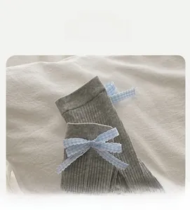 Détail de chaussettes en coton gris avec revers élastique et nœud à carreaux bleu et blanc