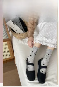 Gros plan de chaussettes en coton gris avec cœurs noirs et bordure à volants doux