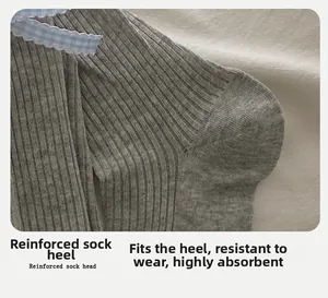 Détail de chaussettes grises à côtes avec nœud à carreaux bleu et talon 3D profilé