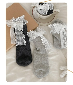 Detail of sweet mid-calf socks with large white lace bows and delicate mesh ruffles