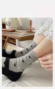 Détail de chaussettes grises à motifs cœurs avec bordure en dentelle et froufrous