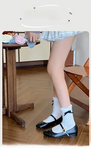 Close-up of white cable knit socks with black bow details and elegant ruffled edges