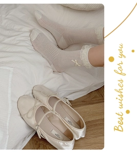 Close-up of ballet style lace socks and satin flats with pearls and bows for women