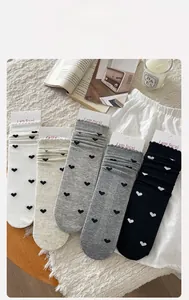 Détail de cinq paires de chaussettes à motif cœur et bords volantés sur lit blanc