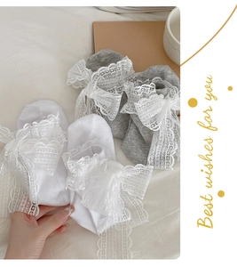 Close-up of white lace bow socks with delicate floral embroidery and ribbon details