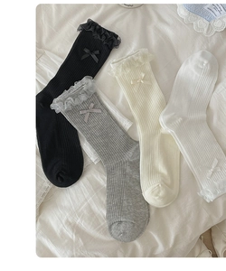 Close-up of four lace-trimmed socks with bows in black, grey, cream, and white colors