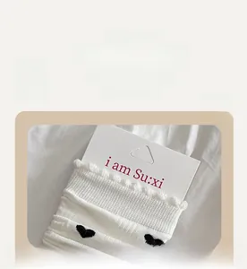 Détail de chaussettes en tricot côtelé blanc avec motifs de cœurs noirs et volants