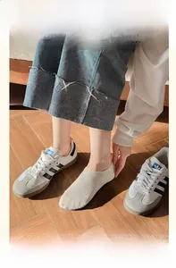 Detail of beige no-show socks with vertical knit texture on woman feet in sneakers