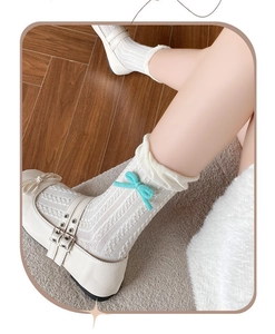 Detail of white textured socks with light blue bows and matte Mary Jane shoes