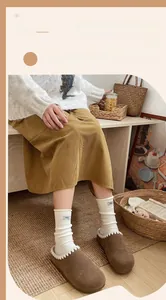 Detail of white wool crew socks with egg letter label paired with plush brown slippers