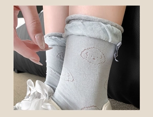 Detail of light blue ballet-style socks featuring a bow and white puppy embroidery