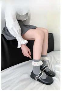 Détail de chaussettes grises avec bordure en dentelle blanche et étiquette logo rouge