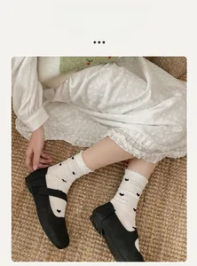 Détail de chaussettes blanches brodées de cœurs avec bordure ondulée et chaussures Mary Jane