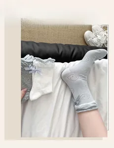 Detail view of ballet-style socks with cute bear print, plaid bows, and lace edges