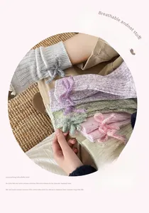 Detail of wool socks with bow accents in grey, pink, purple, and green knit colors