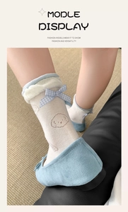 Detail of ballet style white socks with blue bow, lace trim and cartoon dog pattern