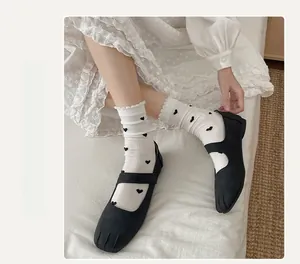 Détail de chaussettes blanches à cœurs noirs avec des chaussures Mary Jane à bout fendu