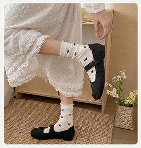 Gros plan de chaussures Mary Jane Tabi noires avec chaussettes à cœurs et jupe dentelle