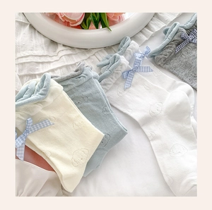 Detail of baby cotton socks with cartoon dog embroidery and ribbon bows in pastel colors