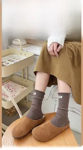Detail of dark brown ribbed wool socks with egg label paired with suede mules