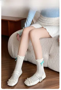Close-up of white agaric lace crew socks with cable knit texture and small blue bow