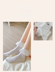 Detail of white cotton socks featuring delicate wavy lace trim and embroidery detail