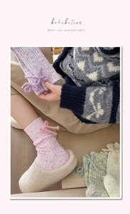 Detail of knitted cashmere socks with bow decoration and thick wool texture in pastel colors
