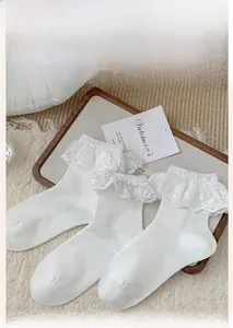 Detailed view of three pairs of white cotton socks with delicate layered lace trim