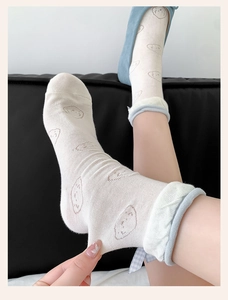 Close-up of white calf socks featuring cartoon prints and elastic blue rolled cuffs