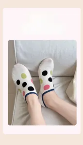 Detailed shot of white cotton blend no-show socks with colorful polka dots on feet