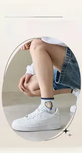 Detail of white cotton sports socks featuring blue stripes and a yellow smiley face icon