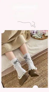Detail of white cashmere socks with grey bow ornament and ribbed knit texture