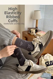 Detail of high-elasticity ribbed cuff on grey mid-tube socks with white bow jacquard