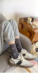 Close-up of dark grey mid-calf socks with white bow jacquard and vertical rib texture