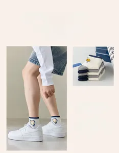 Detail of white cotton sports socks with blue stripes and yellow smiley face embroidery