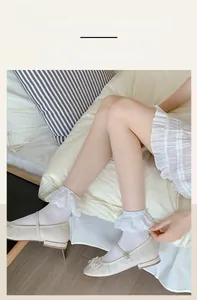 Detailed view of elastic lace ruffles on white socks with pearl Mary Jane flats
