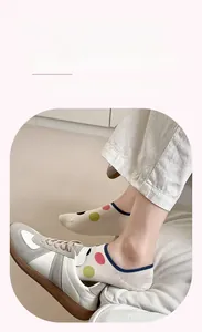 Close-up of beige boat socks with colorful polka dots and navy elastic trim on foot