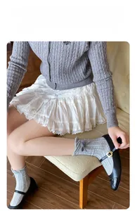 Detail of cable knit crew socks with grey bow paired with black Mary Jane flats
