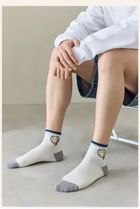 Detail of white cotton sports socks with grey heel patches and a yellow smiley face embroidery