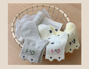 Détails du tricot de chaussettes chat en gris, blanc et beige dans un panier décoratif