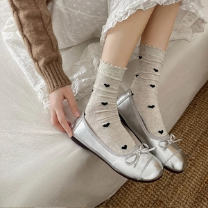 Ballerines argentées à nœud et chaussettes beiges à motifs de cœur en vue de dessus
