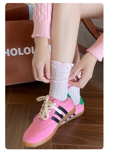 Detail of pink bow socks with intricate floral patterns paired with classic sneakers